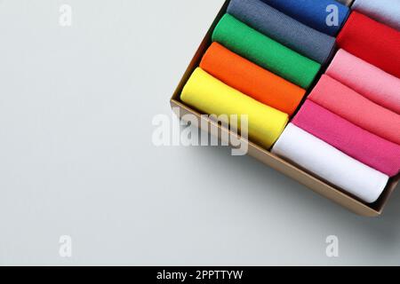 Box mit verschiedenen bunten Socken auf hellem Hintergrund, Draufsicht. Platz für Text Stockfoto