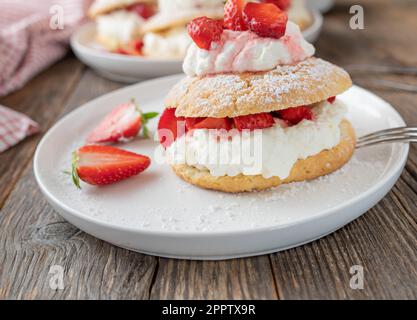 Erdbeergebäck mit Schlagsahne und marinierter Erdbeerfüllung. Traditionelle britische Shortcakes mit kurzer Kruste Stockfoto