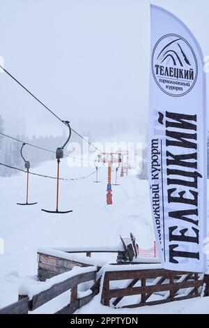 Iogach, Russland - 10. März 2018: Skigebiet Teletsky Altai in der Nähe von Iogach. Aufzug auf dem Berg und Waldhintergrund bei Schneefall. Der Eingang Stockfoto