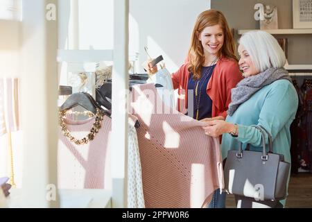 Das war früher mal der Stil. Eine Mutter und Tochter, die in einem Bekleidungsgeschäft einkaufen. Stockfoto