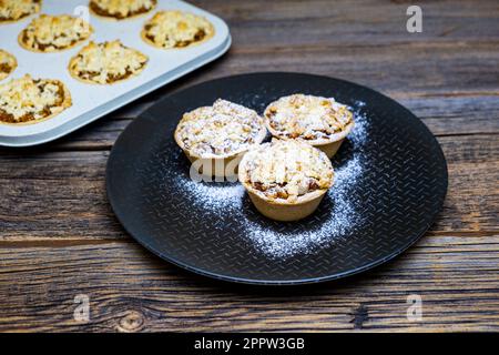 Hausgemachte Apfelkuchen, kleine Apfelkuchen auf rustikalem Holzhintergrund, Nahaufnahme. Stockfoto