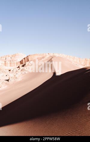 Ein atemberaubendes Bild einer riesigen Wüstenlandschaft mit sanften Sanddünen im Vordergrund und einem wolkenlosen blauen Himmel, der sich bis zum Horizont erstreckt Stockfoto