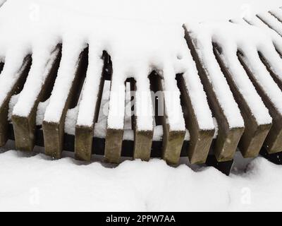 Schneebedeckte Bretter aus Holz aus nächster Nähe im Stadtpark am bedeckten Wintertag Stockfoto