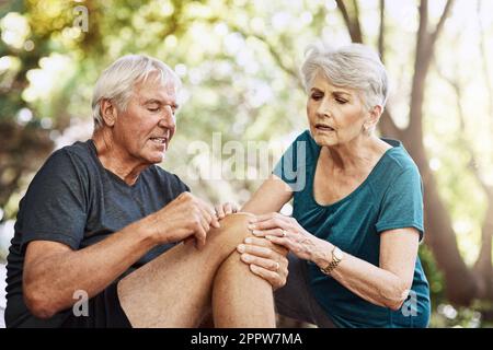 Ich glaube, es könnte verstaucht sein. Ein älterer Mann, der eine Verletzung erlitt, während er mit seiner Frau joggte. Stockfoto
