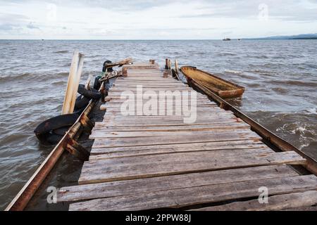 Kleines altes Boot liegt am leeren hölzernen Pier in Samana Bay, Dominikanische Republik Stockfoto