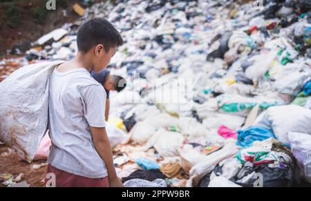 Armer Junge sammelt Müll in seinem Sack, um seinen Lebensunterhalt zu verdienen, das Konzept der armen Kinder und Armut Stockfoto