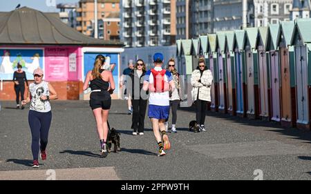 Brighton UK 25. April 2023 - Hove Seafront ist voll mit Wanderer und Läufern an einem sonnigen, aber kühlen Morgen entlang der Südküste : Credit Simon Dack / Alamy Live News Stockfoto