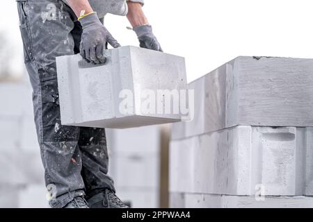 Ein Mauerwerk baut die Wand eines Hauses aus Betonziegeln Stockfoto