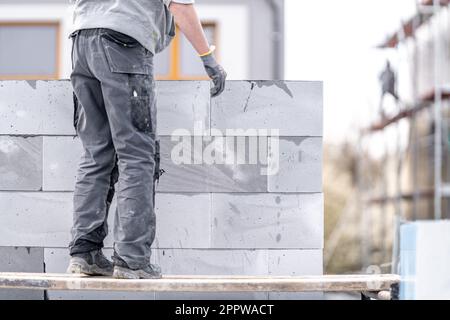 Ein Mauerwerk baut die Wand eines Gebäudes aus Betonziegeln und -Blöcken Stockfoto