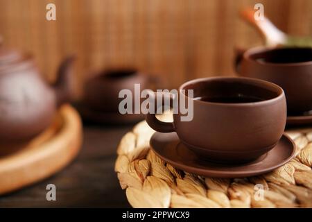 Teezeremonie. Traditionelles Asiatisches Teeutensil, Serviert Authentisches Set. Person, die Tee von der Teekanne aus brauner Keramik bis zur Teekanne einschenkt. Bambusschale. Lifestyle. Wir Stockfoto