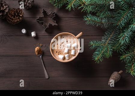 Weihnachtlicher Winterhintergrund mit Kaffee, Kiefernästen und Kegeln auf dunklem Holztisch, Draufsicht. Frohe Weihnachten und ein frohes Neujahrsfest Stockfoto