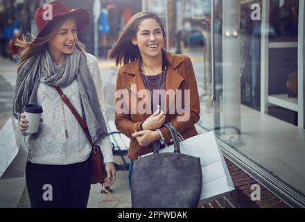 Es gibt nichts Schöneres als Einkaufsmöglichkeiten. Zwei junge Freundinnen, die in der Innenstadt auf einer Shopping-Tour herumlaufen. Stockfoto