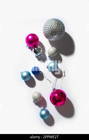 Weihnachtsbaumkugeln, festlich-trendige Komposition mit hartem Licht und Schatten auf weißem Hintergrund. Weihnachten, Neujahr, minimaler kreativer Conce Stockfoto
