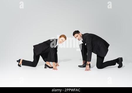 Ernsthafte Mitbewerber in niedriger Startposition, die auf grauen Hintergrund auf die Kamera schauen, Aktienbild Stockfoto