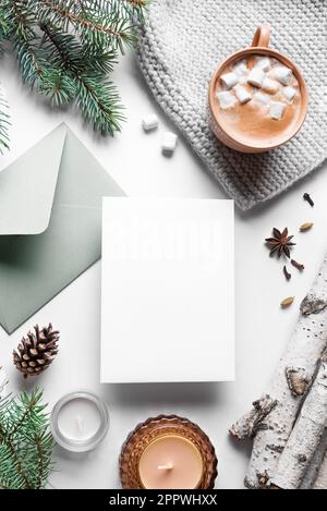 Winterhintergrund mit leerer Karte. Weihnachtseinladungskarte, Tannenzweige, Kiefernzapfen, Kerzen und heißes Kaffeegetränk auf weißem Hintergrund. Trendig Stockfoto