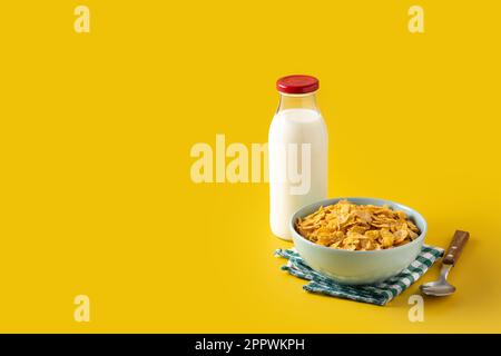 Schüssel mit Müsli und Milchflasche zum Frühstück auf gelbem Hintergrund Stockfoto
