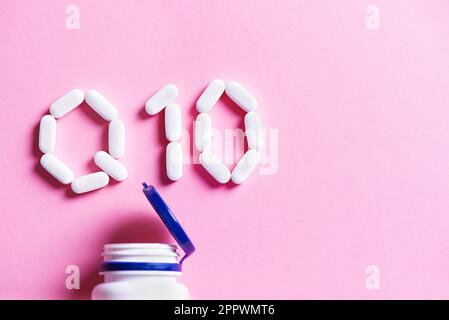 Vitamin-Coenzym Q10. Weiße Pillen Formen sich zu Q10-Zeichen und Plastikflasche auf rosa Hintergrund, Kopierbereich, Draufsicht. Stockfoto