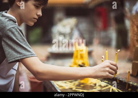 Ein Junge zündet eine Kerze im Wat Doi Suthep Tempel an, Chiang Mai, Thailand Stockfoto