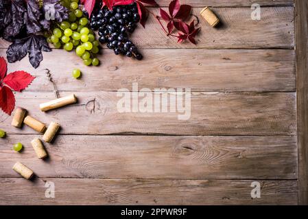 Weinkorken, Korkenzieher und Trauben auf altem Holzhintergrund, Kopierbereich. Konzept für Weinfestival, Weingut oder Weinprobe. Stockfoto