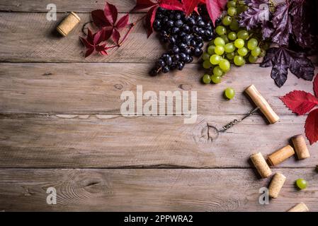 Weinkorken, Korkenzieher und Trauben auf altem Holzhintergrund, Kopierbereich. Konzept für Weinfestival, Weingut oder Weinprobe. Stockfoto