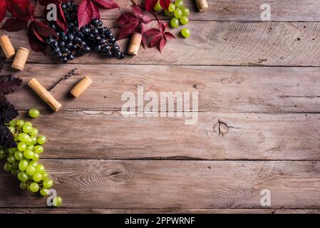 Weinkorken, Korkenzieher und Trauben auf altem Holzhintergrund, Kopierbereich. Konzept für Weinfestival, Weingut oder Weinprobe. Stockfoto