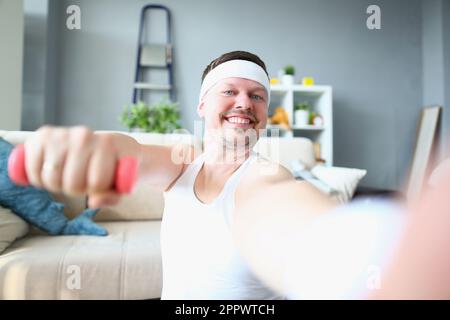 Ein emotional glücklicher, aufgeregter junger Mann, der mit Kurzhanteln posiert und Selfie macht Stockfoto