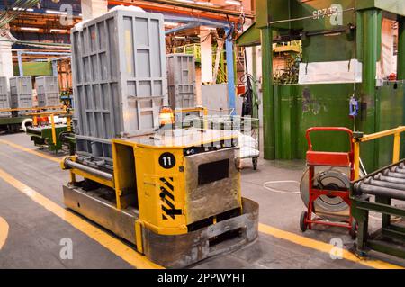 Selbstfahrender, autonomer gelber Metallwagen, Maschine mit Notlichtsignalisierung für die Beförderung von Gütern in der Petroche-Produktionsstätte Stockfoto