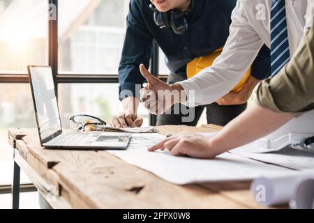 Team asiatischer Ingenieure und Architekten, die erfolgreich ein Projekt aufbauten und dabei Daumen nach oben zeigten und auf ein Notebook blickten Stockfoto