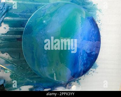 Der Prozess, ein hausgemachtes, modernes, abstraktes Muster zu kreieren, das mit einem Pinsel aus mehrfarbigem Acrylharz auf einem runden Holzbrett bemalt wurde Stockfoto