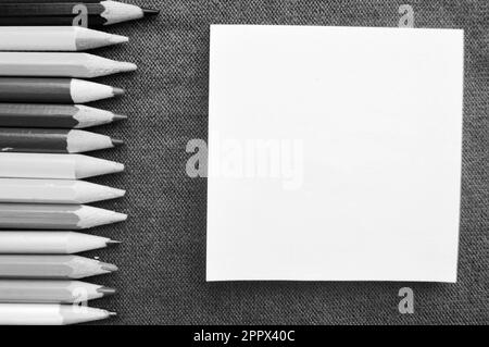 Mehrfarbige, leuchtende, farbenfrohe Bleistifte zum Zeichnen auf der linken Seite und ein Notizblock auf der rechten Seite für Ihren Text auf einem lilafarbenen Texthintergrund. Stockfoto