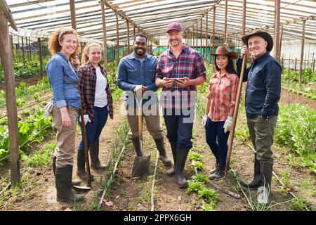 Porträt von lächelnden multikulturellen männlichen und weiblichen Bauern im Gewächshaus Stockfoto