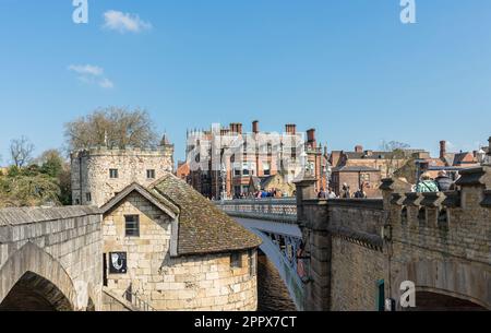 Eine historische Eisenbrücke voller Fußgänger. Auf beiden Seiten befinden sich alte Gebäude aus Stein und Ziegel, und über ihnen ist ein klarer Himmel. Stockfoto