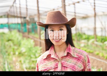 Porträt einer lächelnden Bauernfrau mit Hut auf einem Bio-Bauernhof Stockfoto