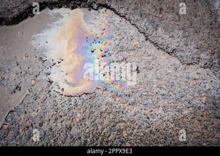 Benzinflecken auf Asphalt. Benzin ist auf der Straße verschüttet. Straße in den Gruben. Stockfoto