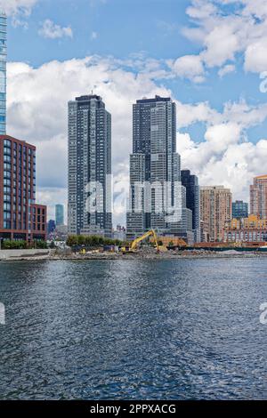 Der zweistöckige Hunter's Point South-Komplex mit Blick auf den East River. Im Vordergrund wird ein neues Projekt mit drei Türmen gebaut. Stockfoto