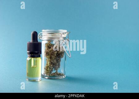 CBD-Extrakt in einer Glasflasche mit einer Pipette, neben trockenen Knospen von medizinischem Marihuana in einem hermetisch versiegelten Gefäß Stockfoto