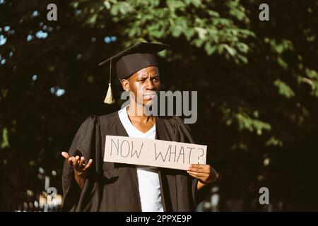 Porträt eines arbeitslosen afro-amerikanischen Mannes, der mit einem Plakat auf der Straße steht, um einen Job zu suchen und über zukünftige Karriere nachzudenken. Universität oder Stockfoto