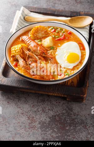 Peruanische Suppe mit Flusskrebsen und Gemüse aus der Nähe auf einem Holzbrett auf dem Tisch. Vertikal Stockfoto