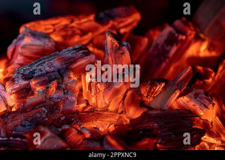 Flamme des Feuers von heißen brennenden Kohlen im Kamin. Wärme aus dem Ofen. Stockfoto