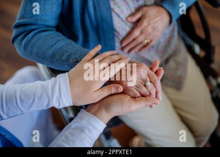 Draufsicht einer Krankenschwester, die die Hände einer Seniorin streichelt. Stockfoto