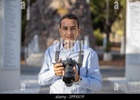 Nahaufnahme eines Fotografen, der mit seiner Kamera in der Hand geradeaus blickt. Stockfoto
