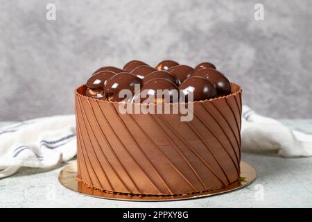 Schokoladengetränkter Profiteroles Geburtstagskuchen. Schokoladenkuchen auf grauem Hintergrund Stockfoto