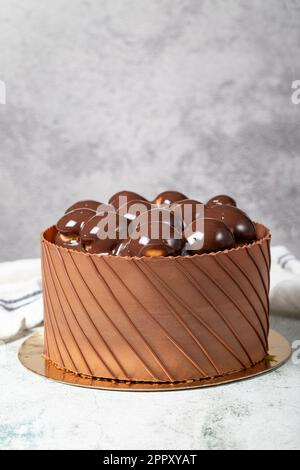 Schokoladengetränkter Profiteroles Geburtstagskuchen. Schokoladenkuchen auf grauem Hintergrund Stockfoto