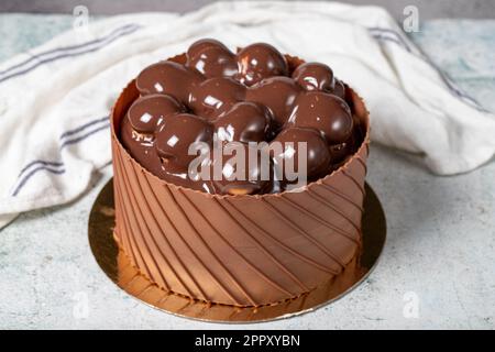 Schokoladengetränkter Profiteroles Geburtstagskuchen. Schokoladenkuchen auf grauem Hintergrund. Schließen Stockfoto