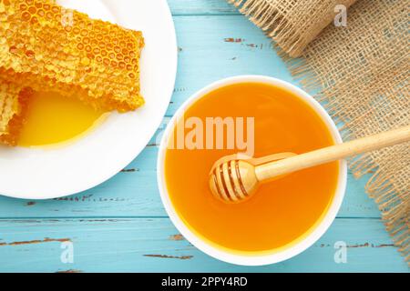 Schüssel mit Honig mit Wabenmuster auf blauem Holztisch. Draufsicht Stockfoto