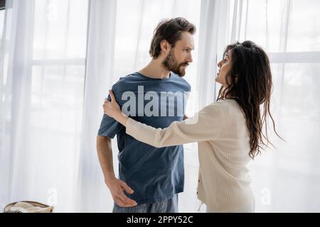 Ängstliche Frau, die sich zu Hause mit einem wütenden Freund berührt und mit ihm spricht, während eines Konflikts, Börsenbild Stockfoto