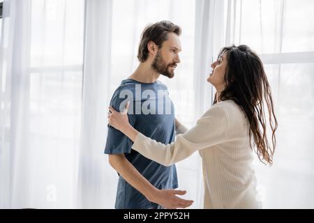 Aggressiver Mann, der verängstigte Freundin während einer Beziehungskrise zuhause ansieht, Aktien-Image Stockfoto