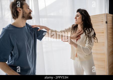 Missbräuchlicher Mann schubst verängstigte Freundin zu Hause in Pyjama, Börsenbild Stockfoto