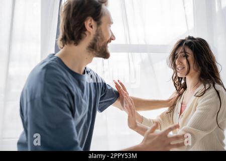 Ängstliche Frau, die einen wütenden Freund während eines Konflikts zu Hause mit einer Stoppgeste behandelt, Börsenbild Stockfoto