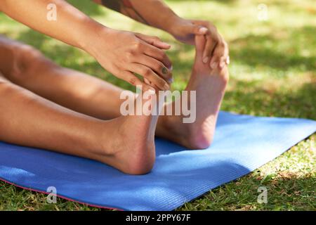 Nahaufnahme einer jungen Frau, die sich im Sommer auf der Yoga-Matte im Freien dehnt Stockfoto